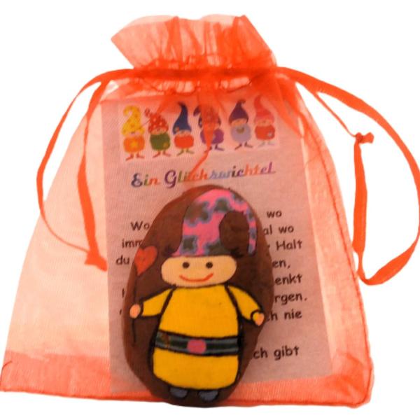 Gelber Glückswichtel mit bunter Mütze im Säckchen